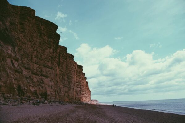 Tall sandstone cliffs above a quiet sandy beach and calm sea